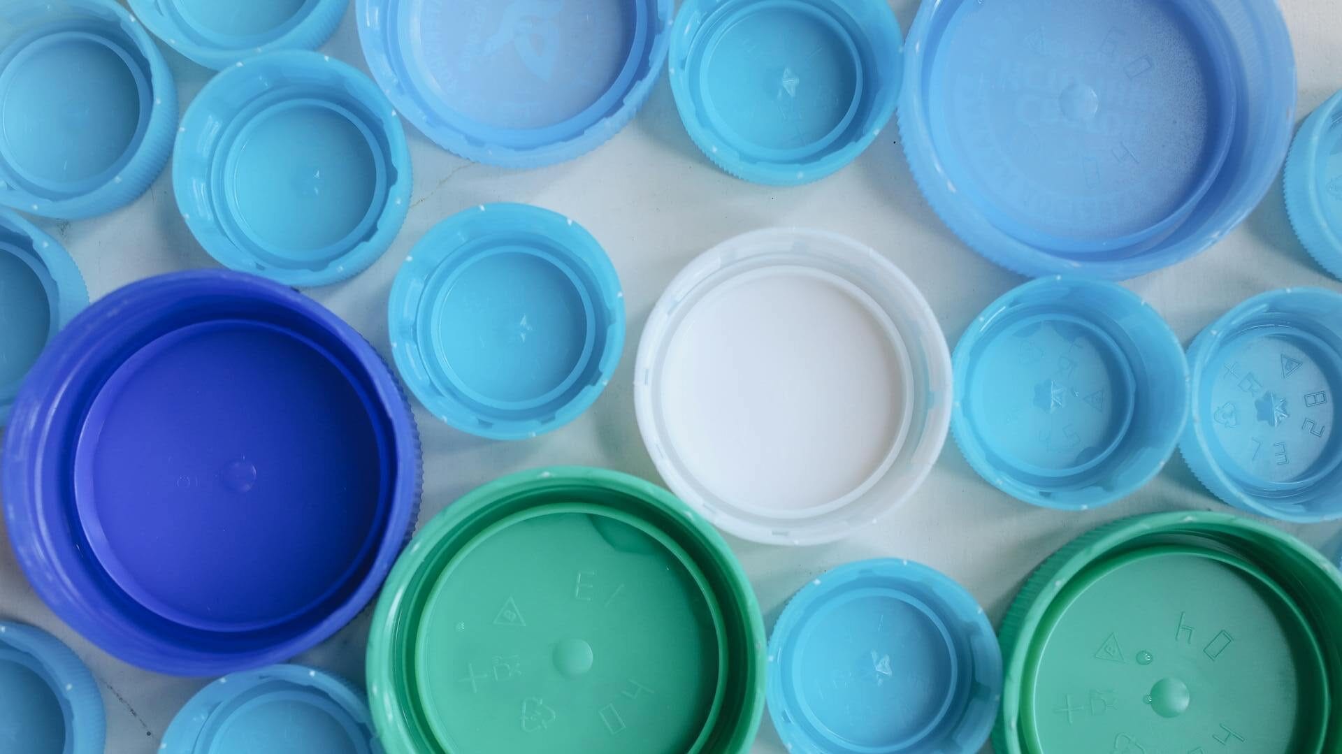 The picture showcases a collection of plastic bottle caps in various shades of blue and white. 